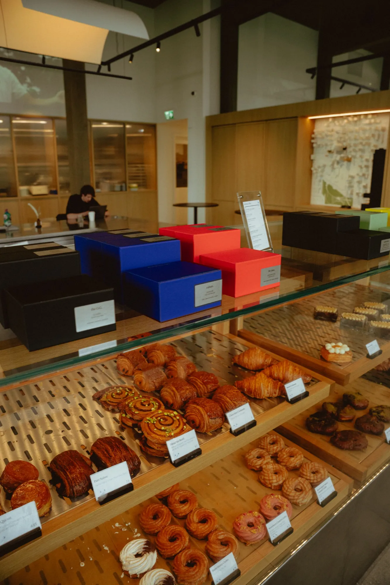Artisan pastry display case with fresh croissants, danish pastries, and colorful gift boxes