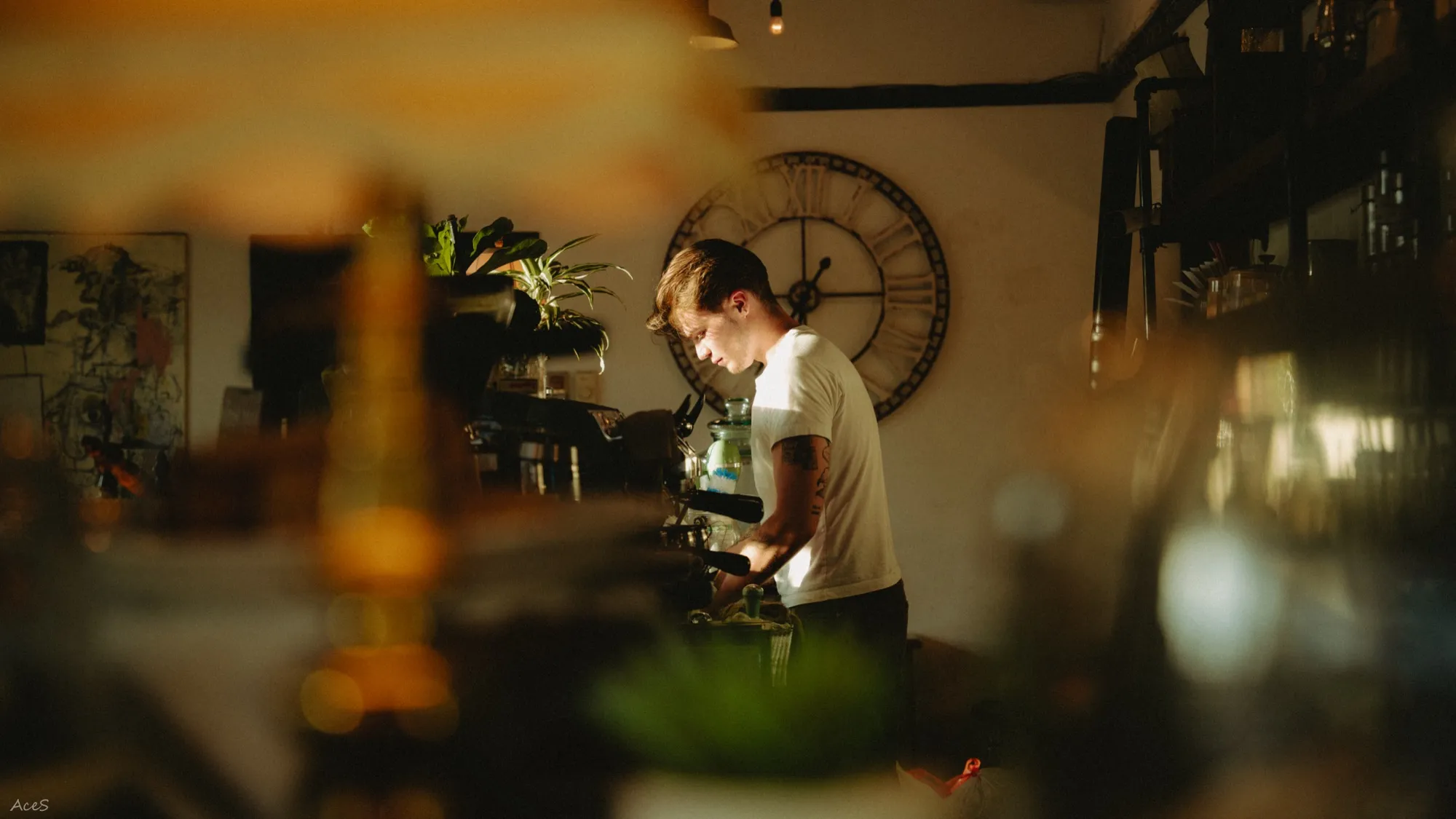 Barista making coffee with dreamy bokeh foreground in warm golden evening light