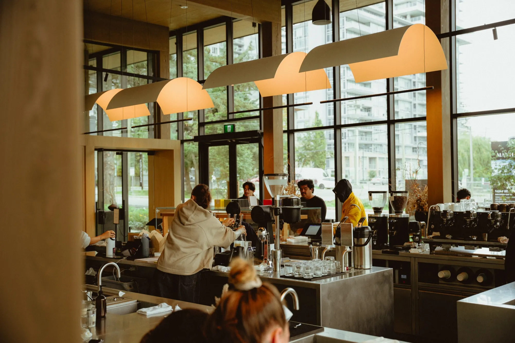 Baristas working at busy espresso bar with dome pendant lights and professional coffee equipment