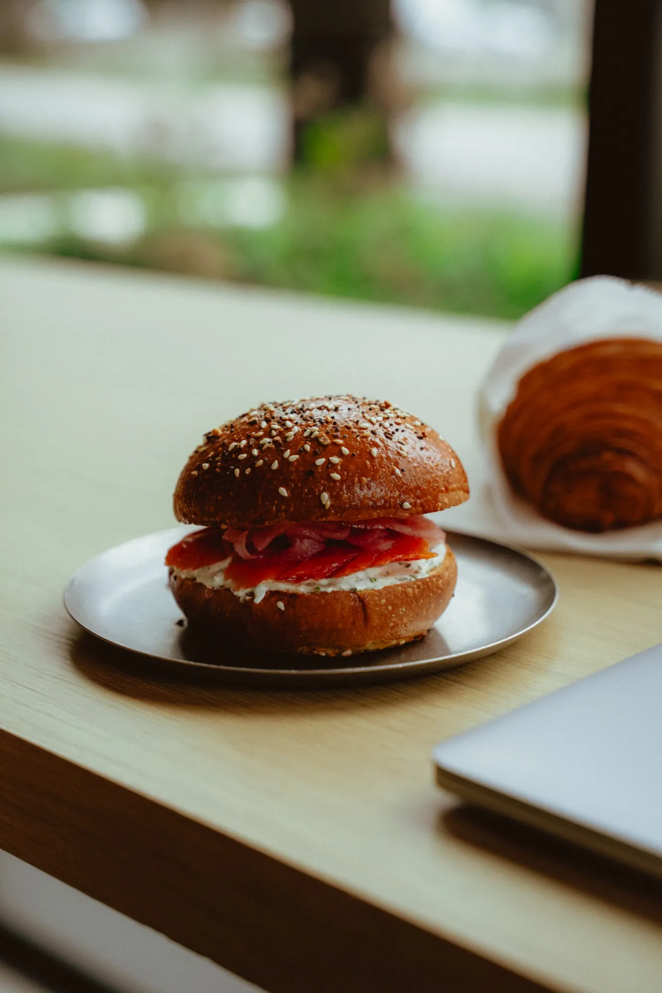Smoked salmon bagel sandwich and fresh croissant on cafe window counter
